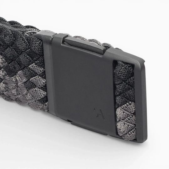 A close-up of the Arcade Belts Futureweave, a black and gray woven webbing paracord belt featuring a matte black rectangular buckle, set against a white background.