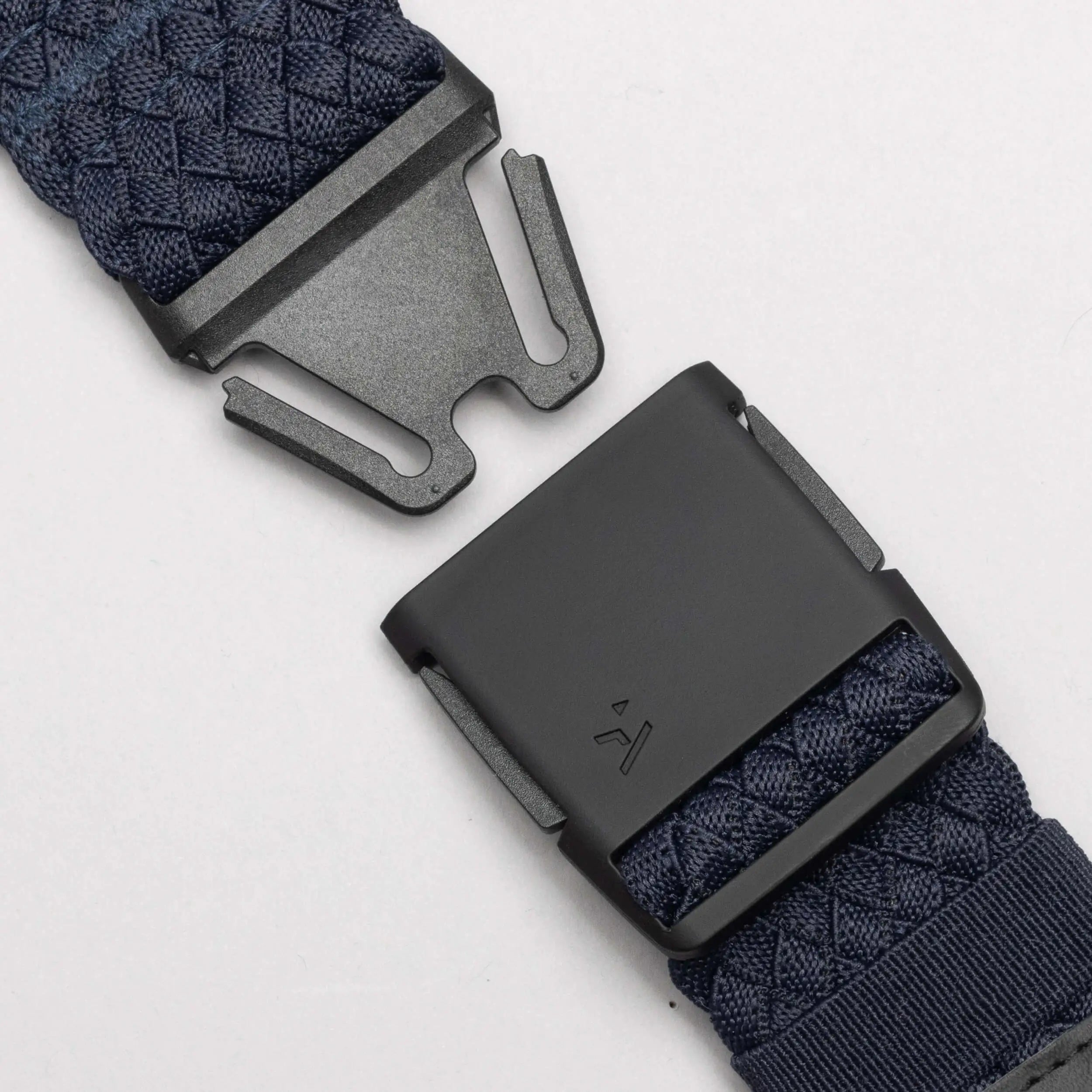 Close-up of the Arcade Belts Futureweave, a navy blue woven webbing belt with a matte black metal buckle, shown partially unfastened on a light gray background for a comfortable, lightweight fit.