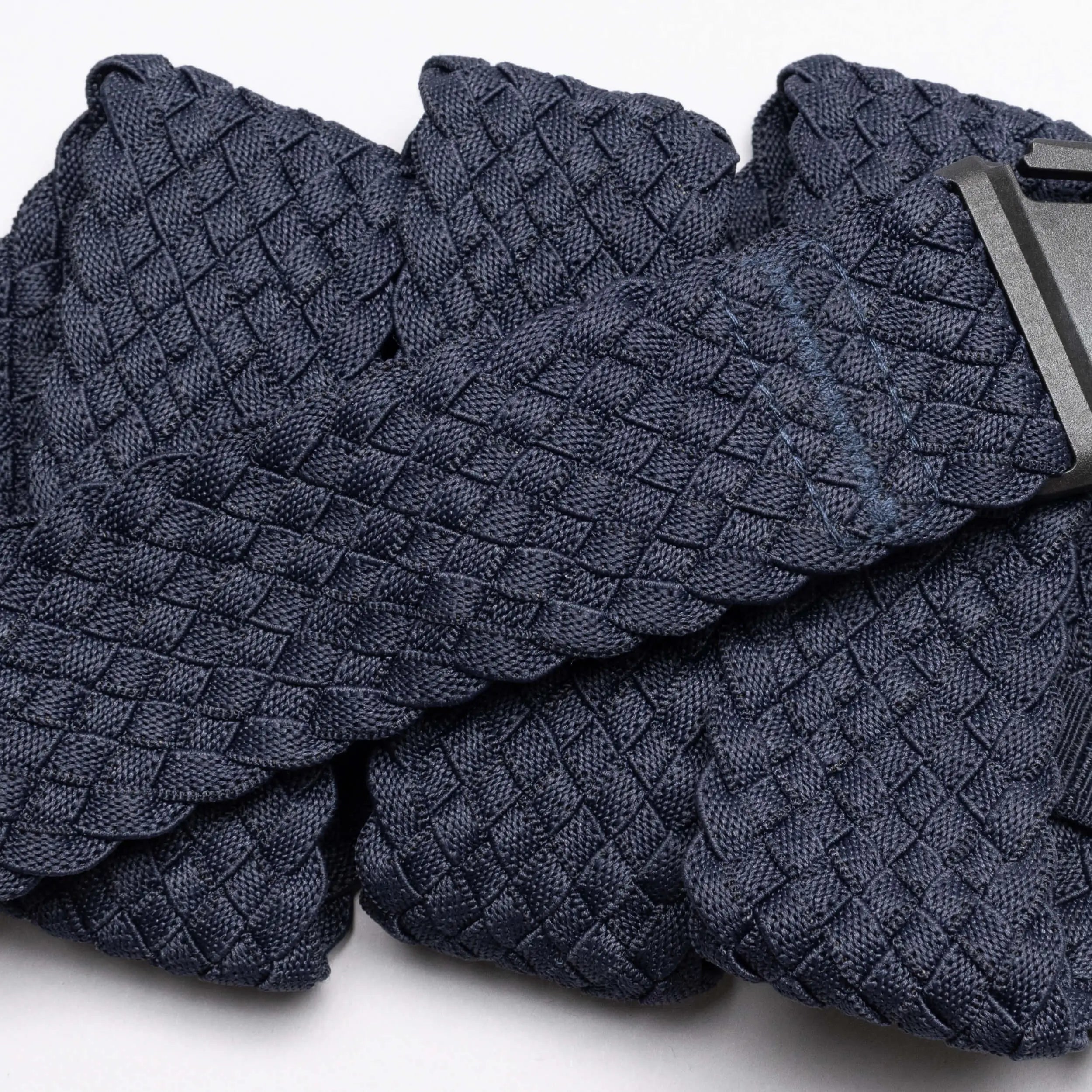 A close-up of the Arcade Belts Futureweave—a navy blue braided belt made from textured woven webbing with a black buckle—offers a comfortable option, shown on a white background.