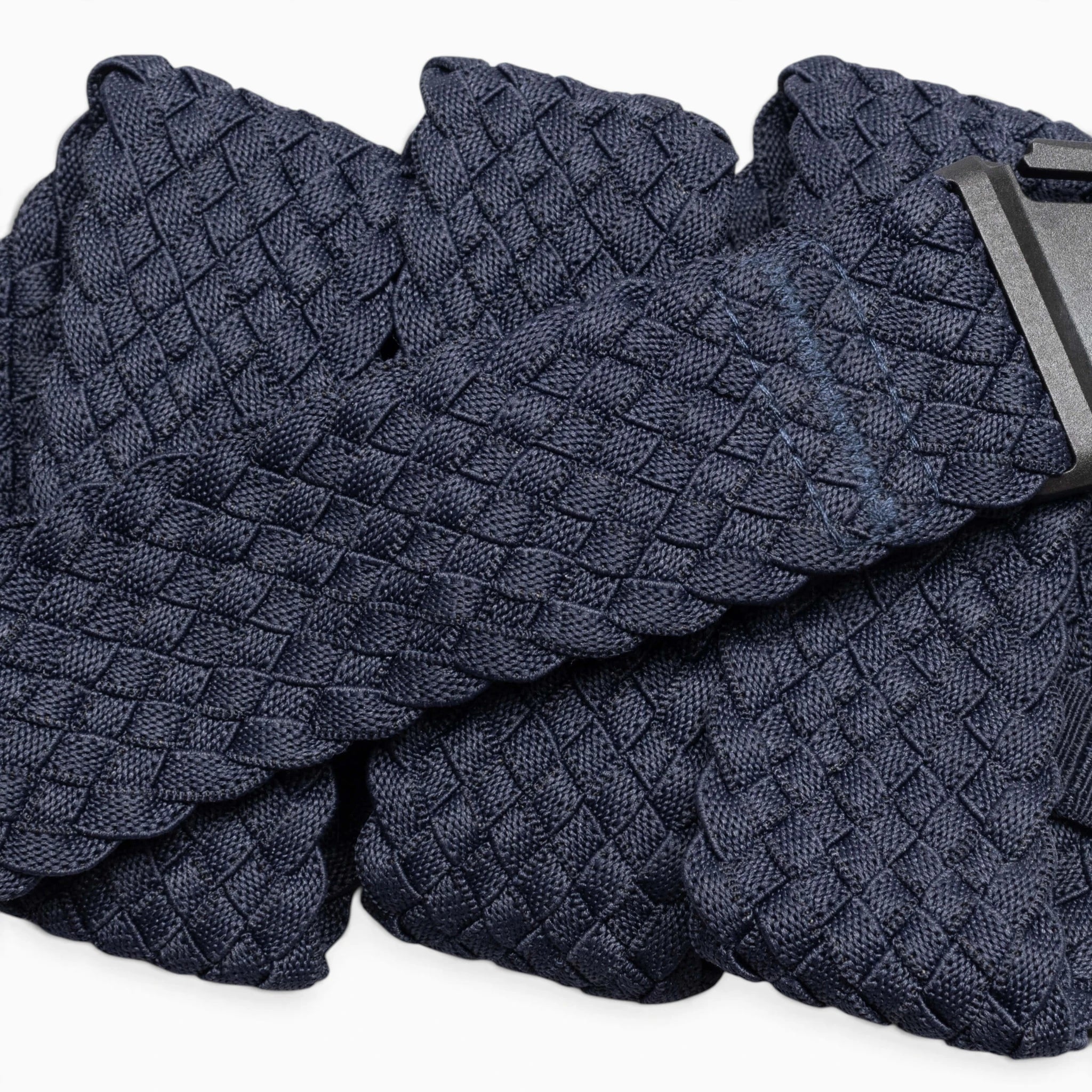 A close-up of the Arcade Belts Futureweave, a navy blue braided belt with a woven webbing texture and a black rectangular buckle, displayed against a white background. This lightweight belt combines style and comfort.
