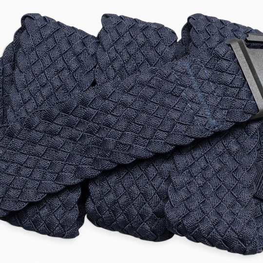 A close-up of the Arcade Belts Futureweave, a navy blue braided belt with a woven webbing texture and a black rectangular buckle, displayed against a white background. This lightweight belt combines style and comfort.