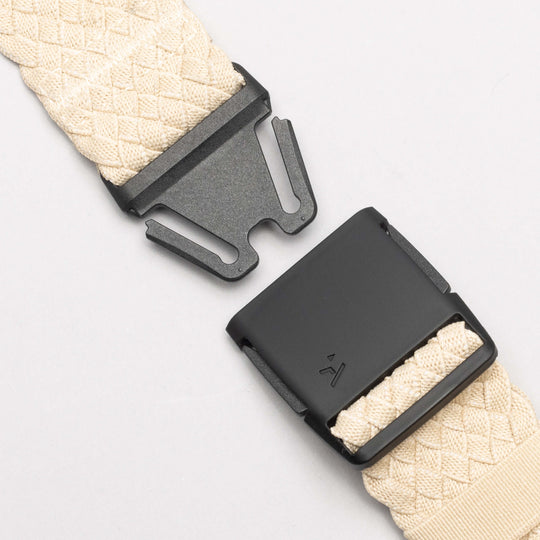 Close-up of the Futureweave belt by Arcade Belts in beige, featuring a black metal buckle and clasp, displayed unfastened on a light gray background.