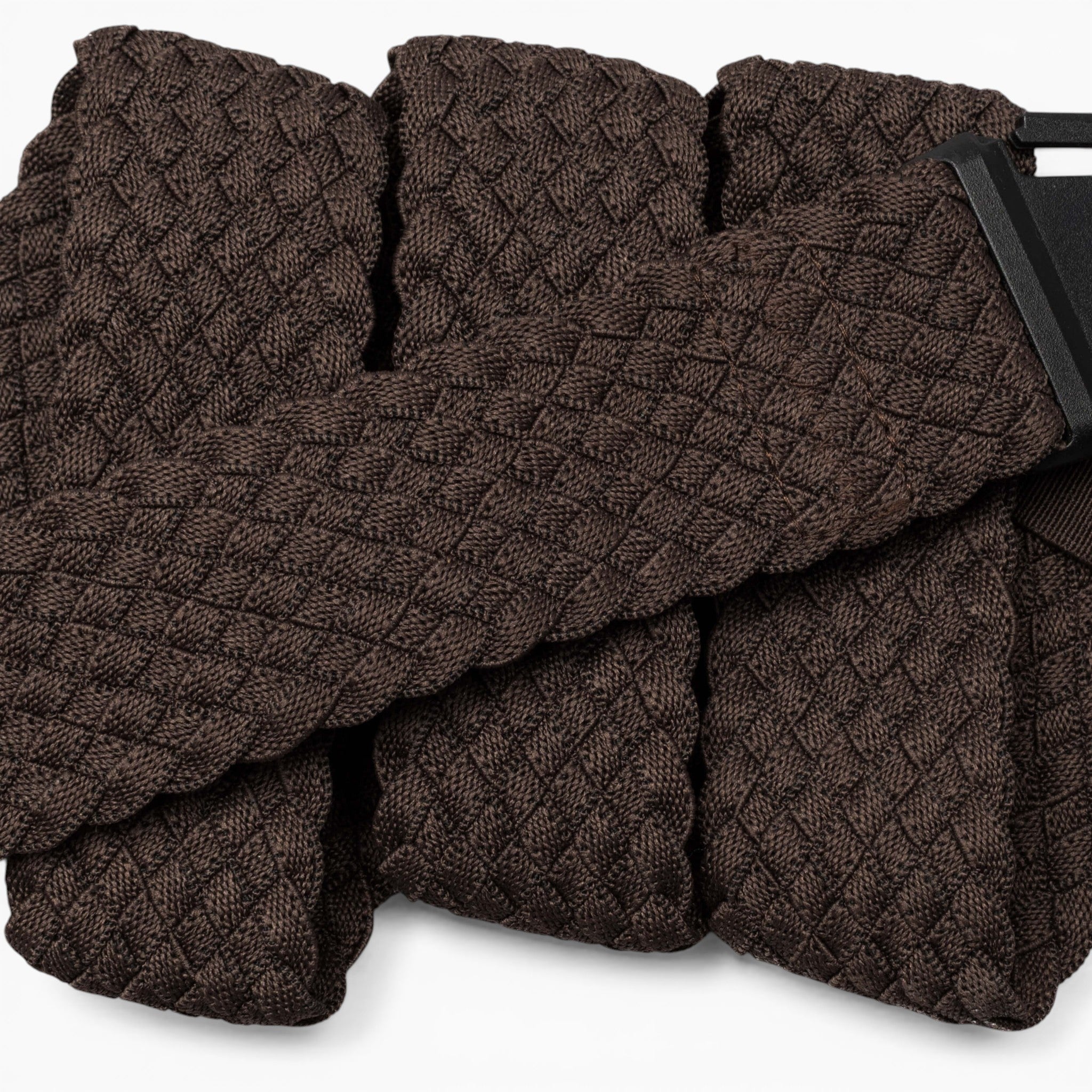 A close-up of the Arcade Belts Futureweave, a textured dark brown belt with a geometric diamond pattern, crafted from lightweight woven webbing for all-day comfort and featuring a partially visible rectangular black metal buckle.