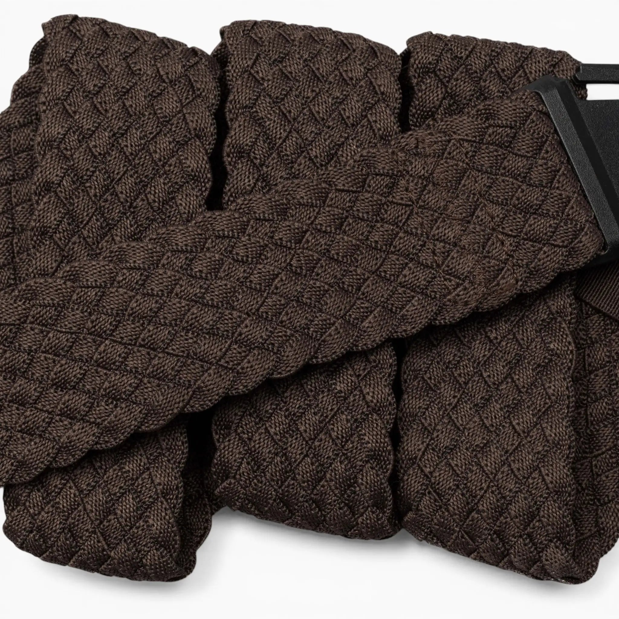 A close-up of the Arcade Belts Futureweave, a textured dark brown belt with a geometric diamond pattern, crafted from lightweight woven webbing for all-day comfort and featuring a partially visible rectangular black metal buckle.