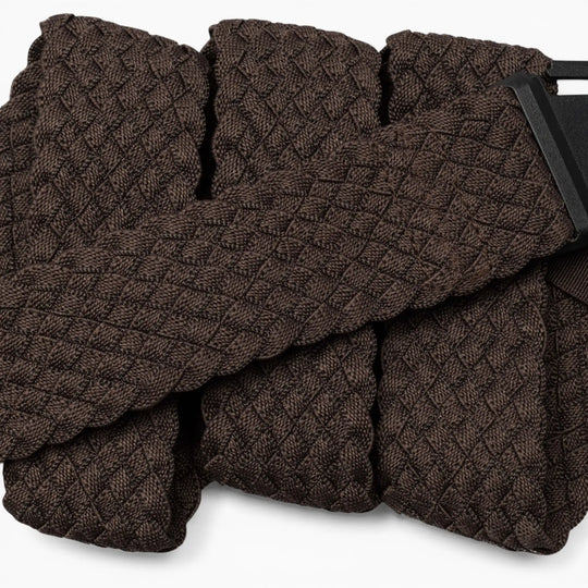 A close-up of the Arcade Belts Futureweave, a textured dark brown belt with a geometric diamond pattern, crafted from lightweight woven webbing for all-day comfort and featuring a partially visible rectangular black metal buckle.