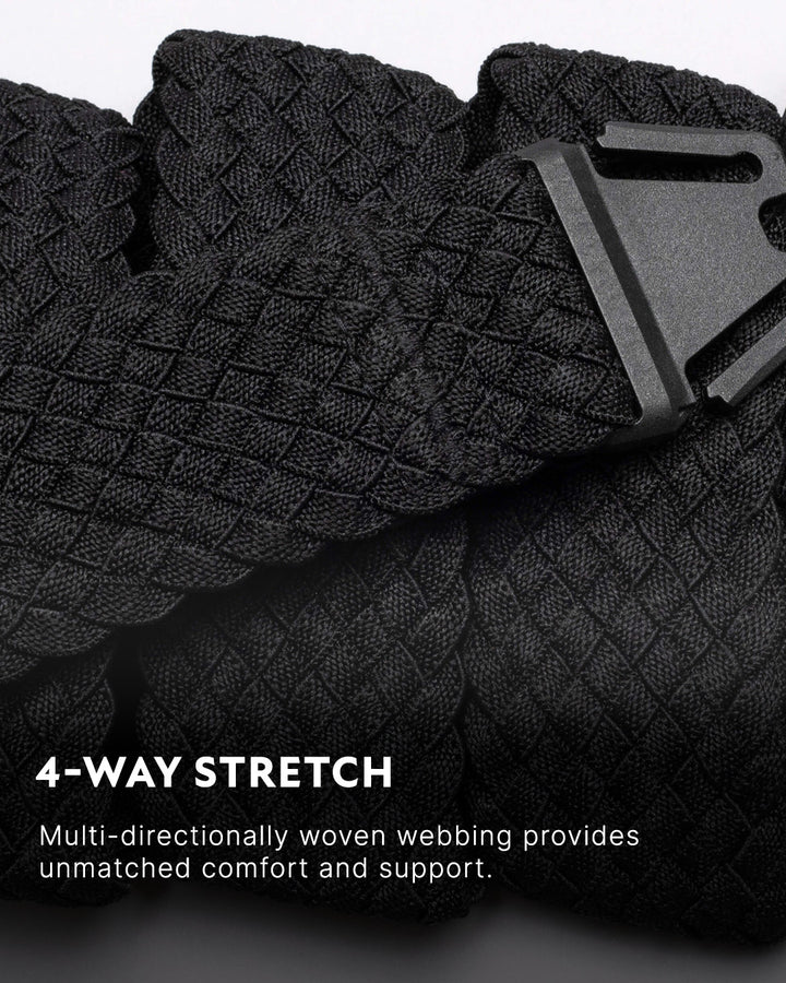 Close-up of a black, multi-directionally woven Low Profile Belt with a plastic buckle. Text reads: 4-WAY STRETCH. Stretch webbing provides unmatched comfort and support for travel or everyday wear.