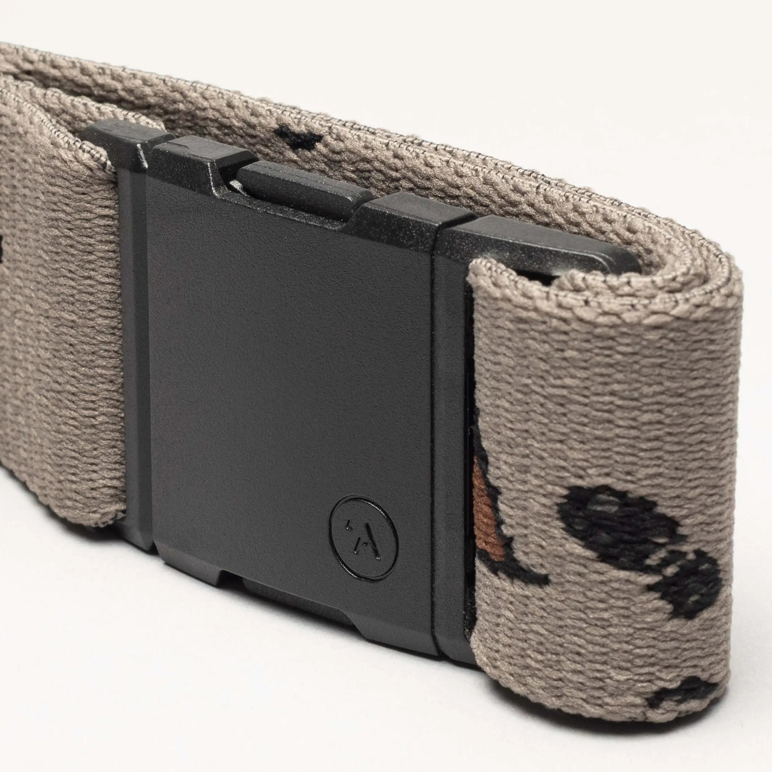 A close-up of the Arcade Belts Get Outside tan hiking belt, featuring a black rectangular buckle and a subtle pattern of small black and brown shapes. Ideal for outdoor adventures, shown against a plain light background.