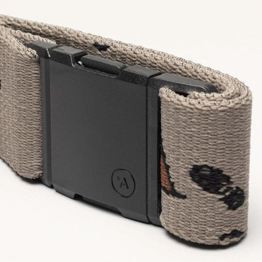 A close-up of the Arcade Belts Get Outside tan hiking belt, featuring a black rectangular buckle and a subtle pattern of small black and brown shapes. Ideal for outdoor adventures, shown against a plain light background.