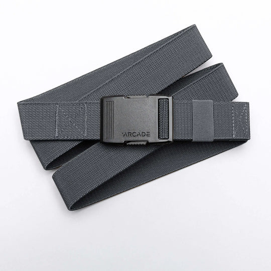 A gray woven Arcade Belts Hardware belt with superior strength and a black ARCADE-labeled plastic buckle is coiled loosely on a white background.