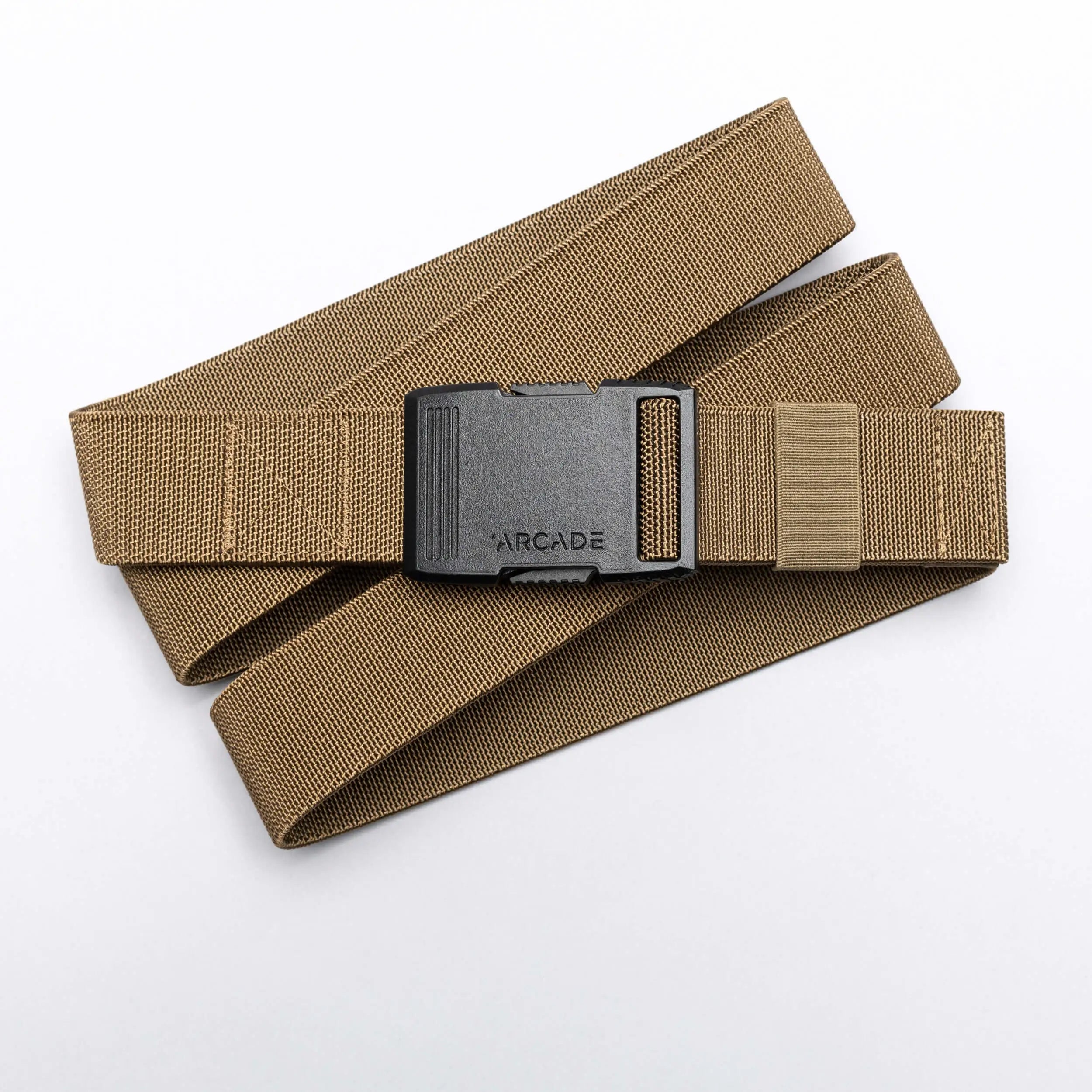 A tan Arcade Belts Hardware elastic stretch belt with a black plastic buckle, labeled ARCADE, is coiled neatly on a white background.