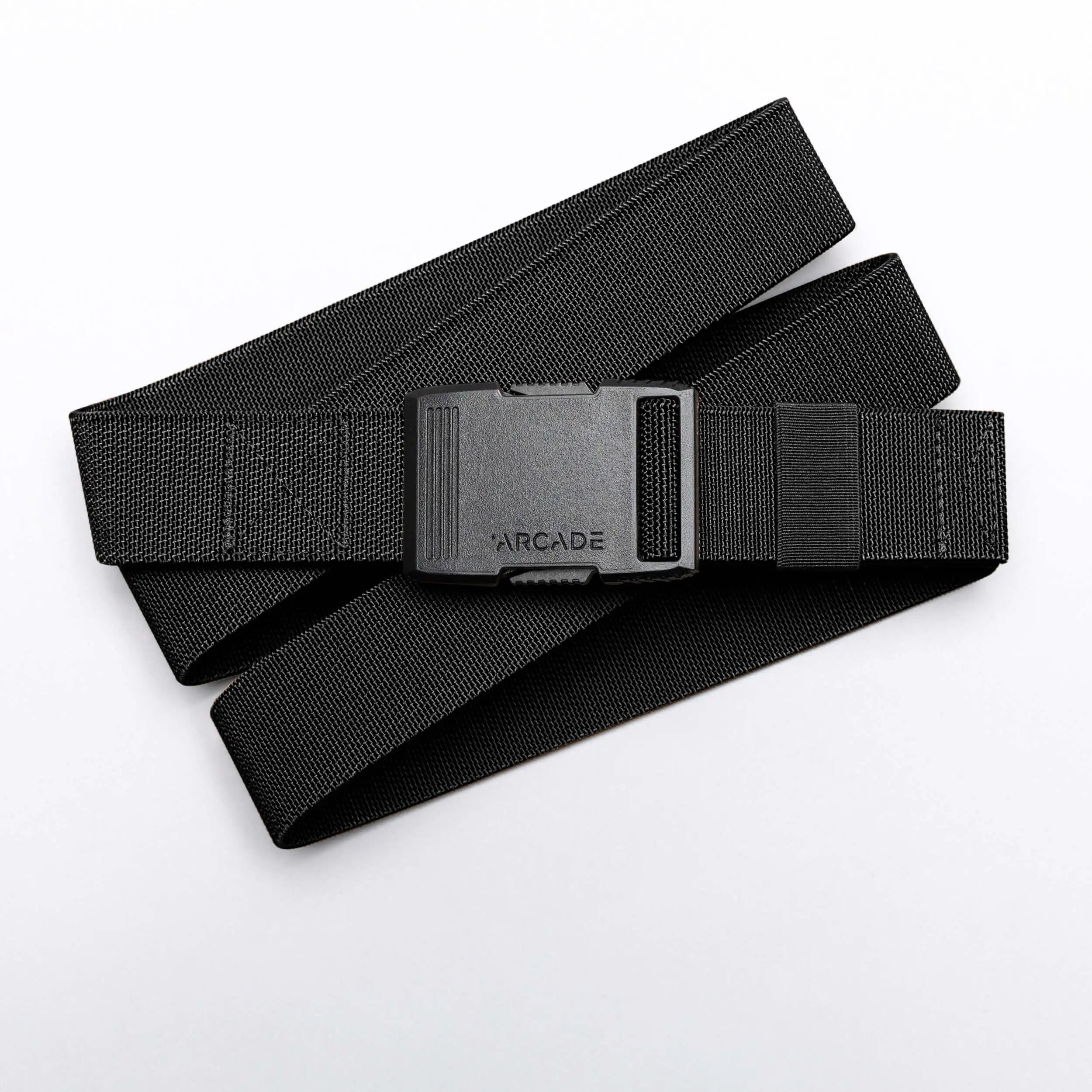 The Arcade Belts Hardware is a black elastic stretch belt with a low profile buckle engraved with ARCADE, neatly coiled on a white background.