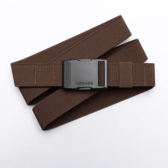 The Arcade Belts Hardware is a brown stretch webbing belt with a low profile and a black rectangular buckle labeled ARCADE, shown coiled on a white background.