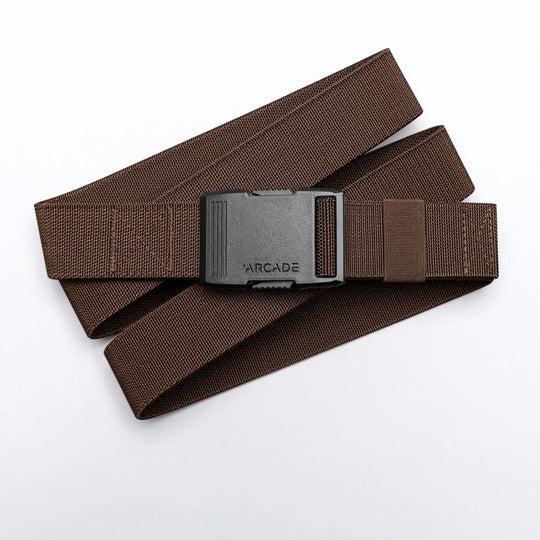 The Arcade Belts Hardware is a brown stretch webbing belt with a low profile and a black rectangular buckle labeled ARCADE, shown coiled on a white background.
