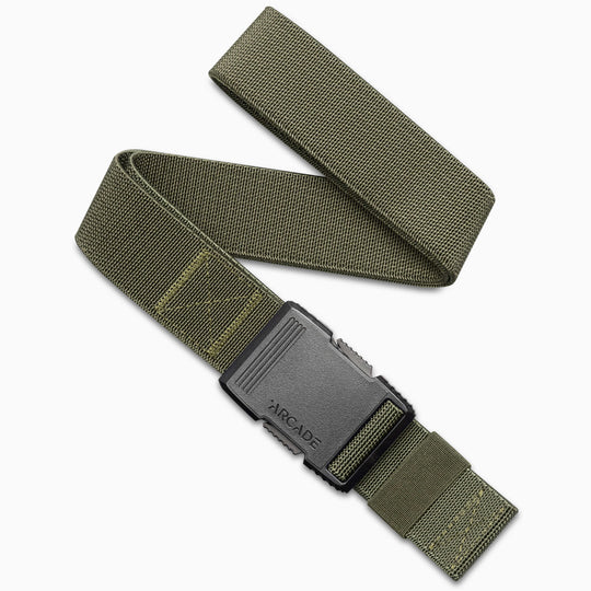 The Arcade Belts Hardware is a green elastic stretch belt with a black plastic buckle embossed with ARCADE, shown coiled in an S shape on a white background—a perfect travel belt thanks to its flexible stretch webbing design.