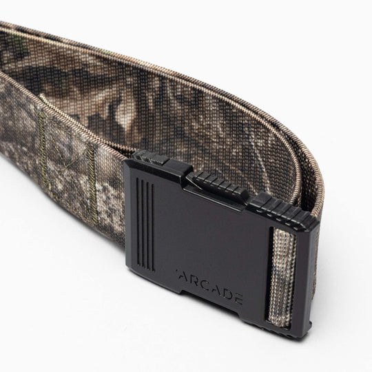 A close-up of the Arcade Belts Hardware, a camouflage-patterned belt with a low profile design and black buckle engraved with ARCADE, displayed on a white background.