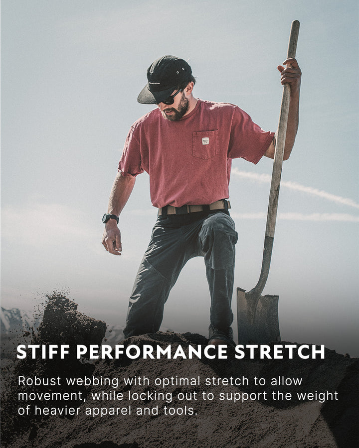 A man in sunglasses and a red t-shirt stands on a mound of dirt, holding a shovel. Text below reads: Arcade Belts STIFF PERFORMANCE STRETCH. Robust stretch webbing delivers movement and support for heavier apparel and tools.