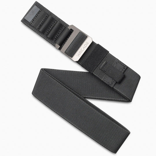 The Arcade Belts Hardware Alu Long Kit is a black fabric travel belt with a low-profile, rectangular plastic buckle engraved with ARCADE, shown neatly coiled on a white background.