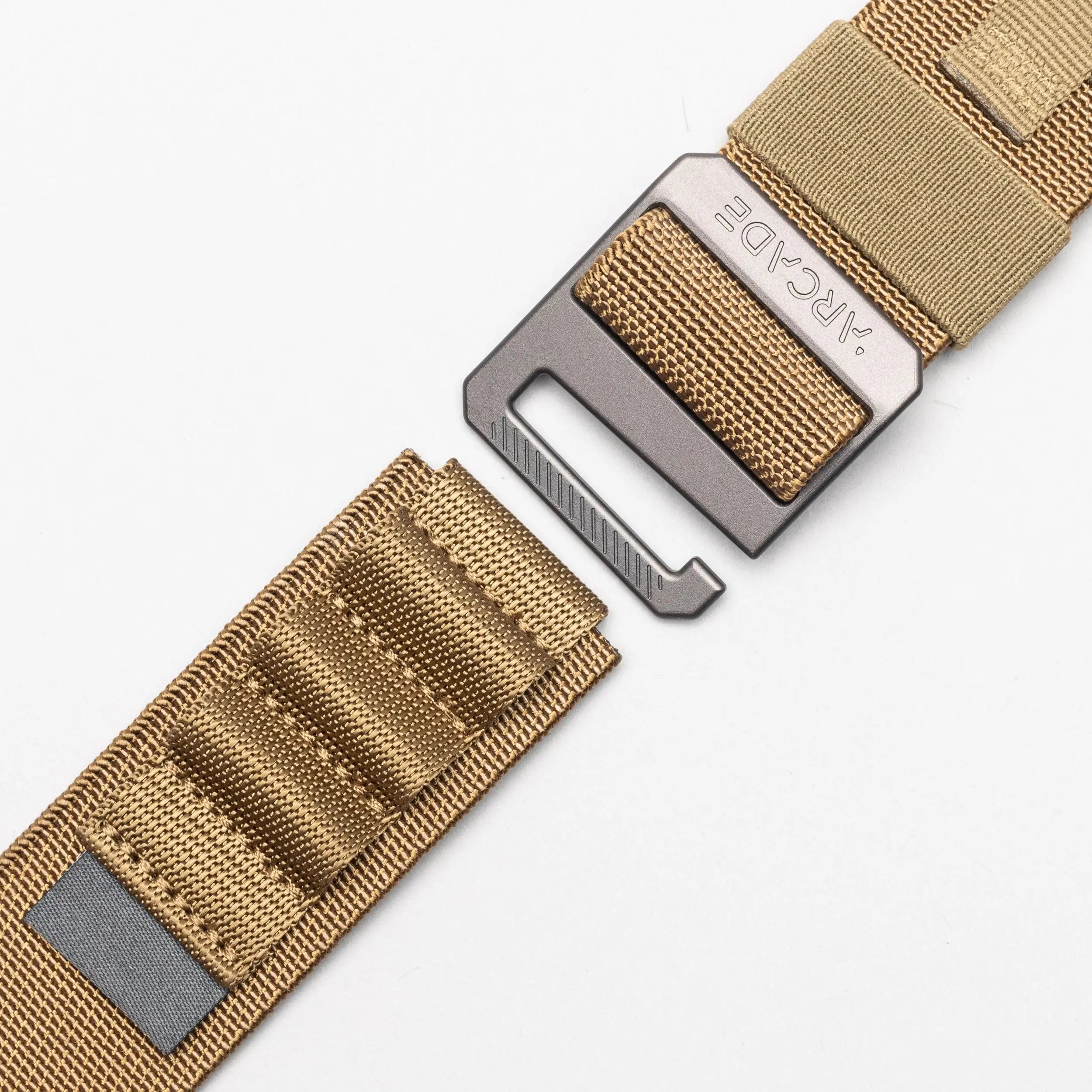 A close-up of the tan nylon Arcade Belts Hardware Alu belt with a metal buckle, set against a white background; the buckle and strap are partially separated.