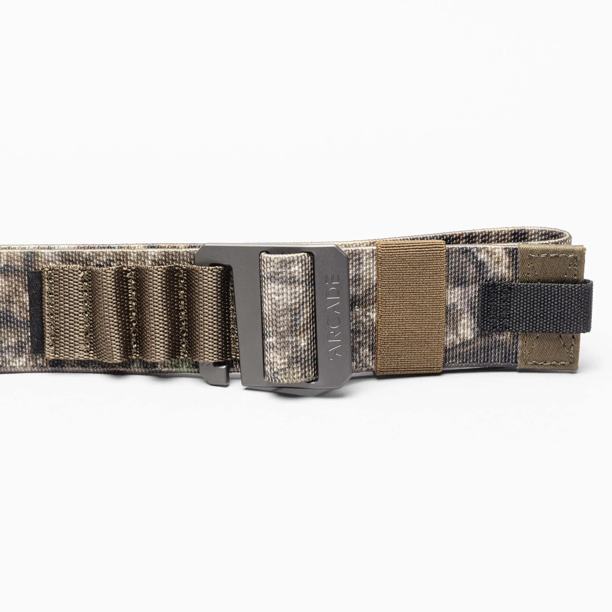 The Hardware Alu by Arcade Belts is a camouflage-patterned travel belt with a matte black plastic buckle, stretch webbing, elastic loops, and brown and black accents, shown coiled on a white background.