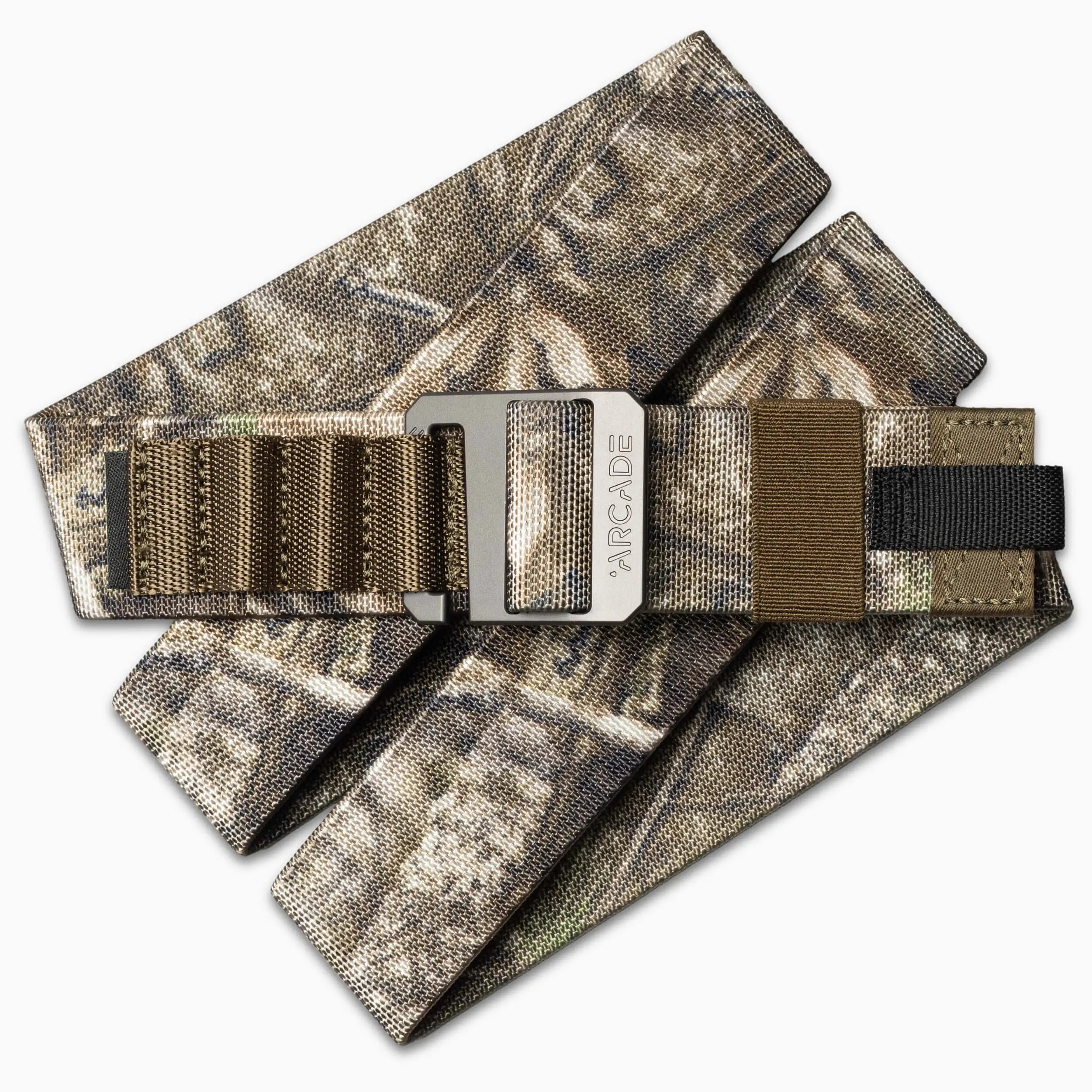 The Arcade Belts Hardware Alu is a camouflage-patterned fabric belt with brown and black webbing, featuring a brushed metal buckle engraved with the brand name for added style.
