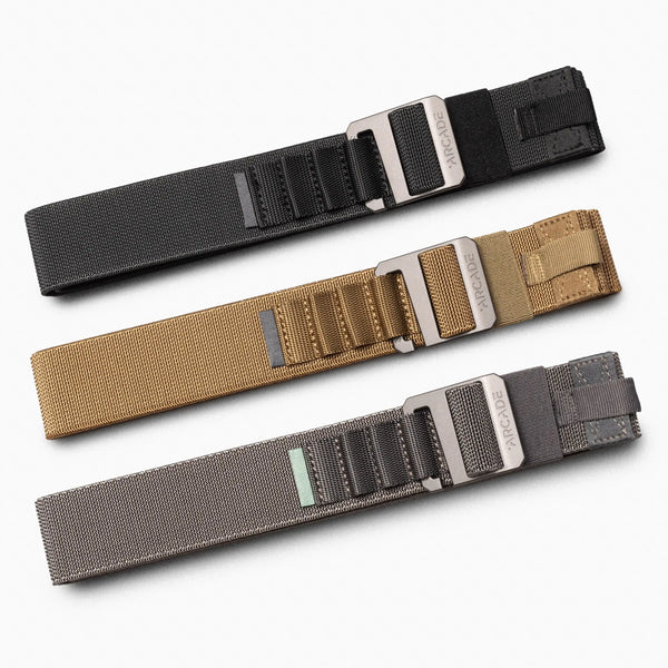 Three Arcade Belts Hardware Alu Kit nylon belts in black, tan, and gray with silver metal buckles and multiple loops are laid out side by side on a light background—ideal for everyday style.