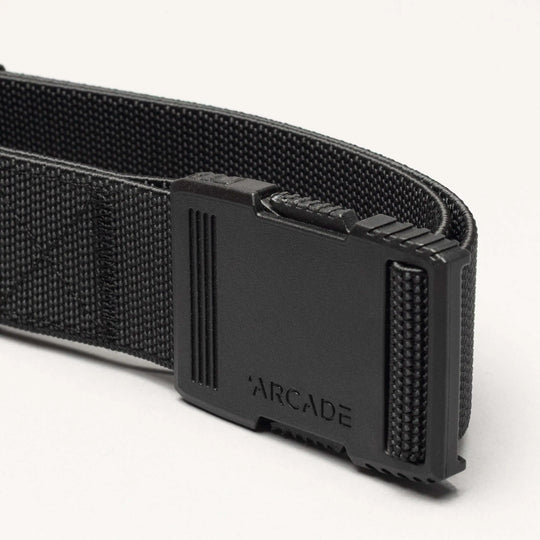Close-up of the Arcade Belts Hardware belt with a rectangular plastic buckle and ARCADE embossed on it, highlighting its superior strength against a plain light background.