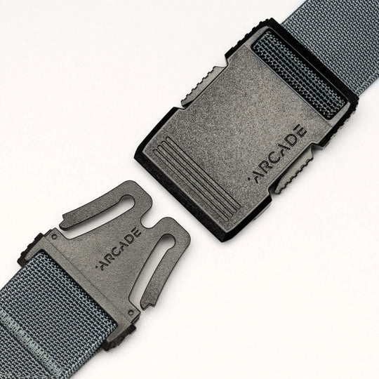 Close-up of a grey fabric Arcade Belts Hardware belt with a black plastic buckle, both parts separated and facing each other, showcasing the product’s superior strength and modern style.