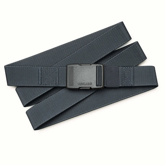 An Arcade Belts Hardware belt in black with a rectangular plastic buckle rests flat and loosely folded in a zigzag pattern on a light background—an essential accessory known for its superior strength.