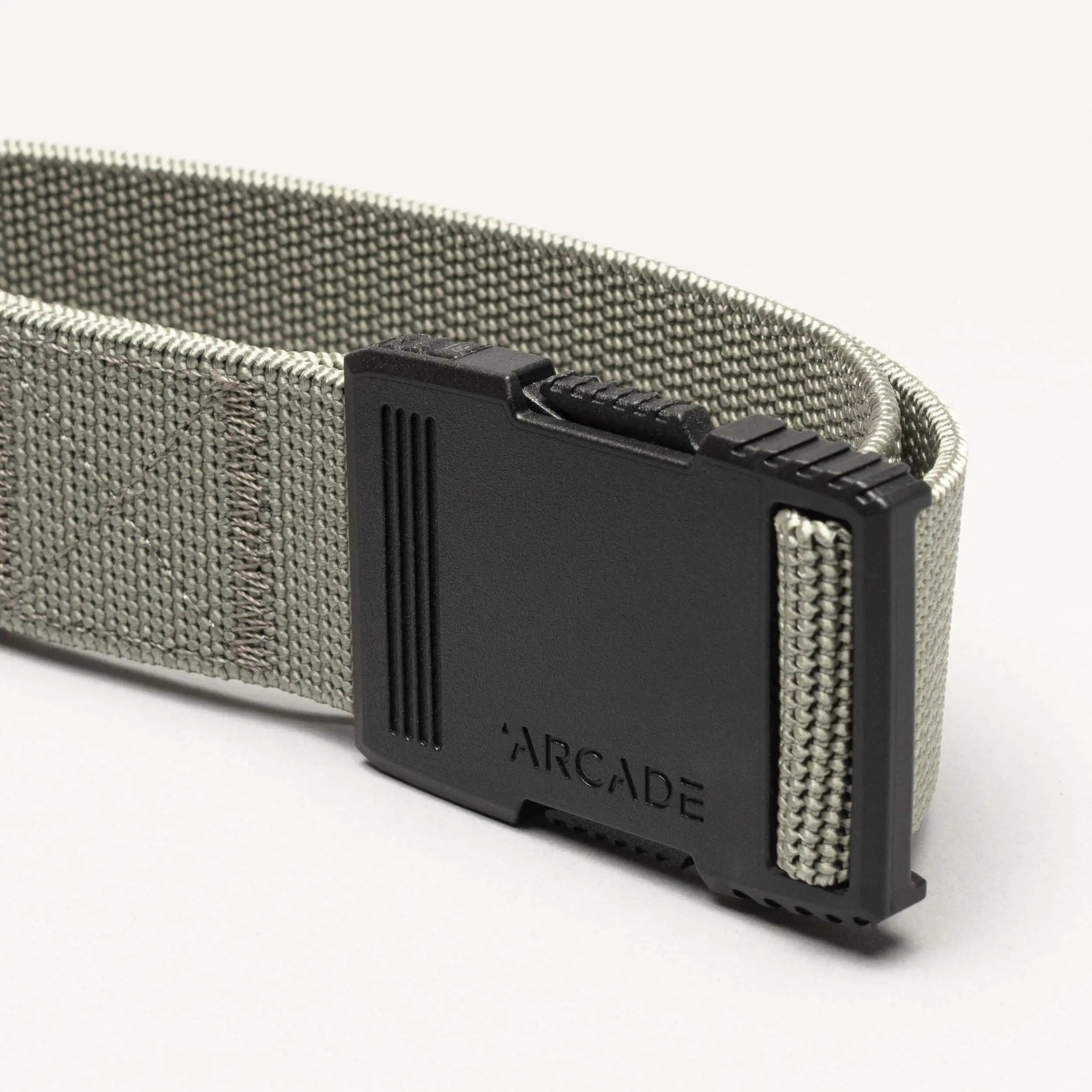 A close-up of the gray Hardware belt by Arcade Belts, featuring superior strength and a black plastic buckle engraved with ARCADE, shown against a light background.