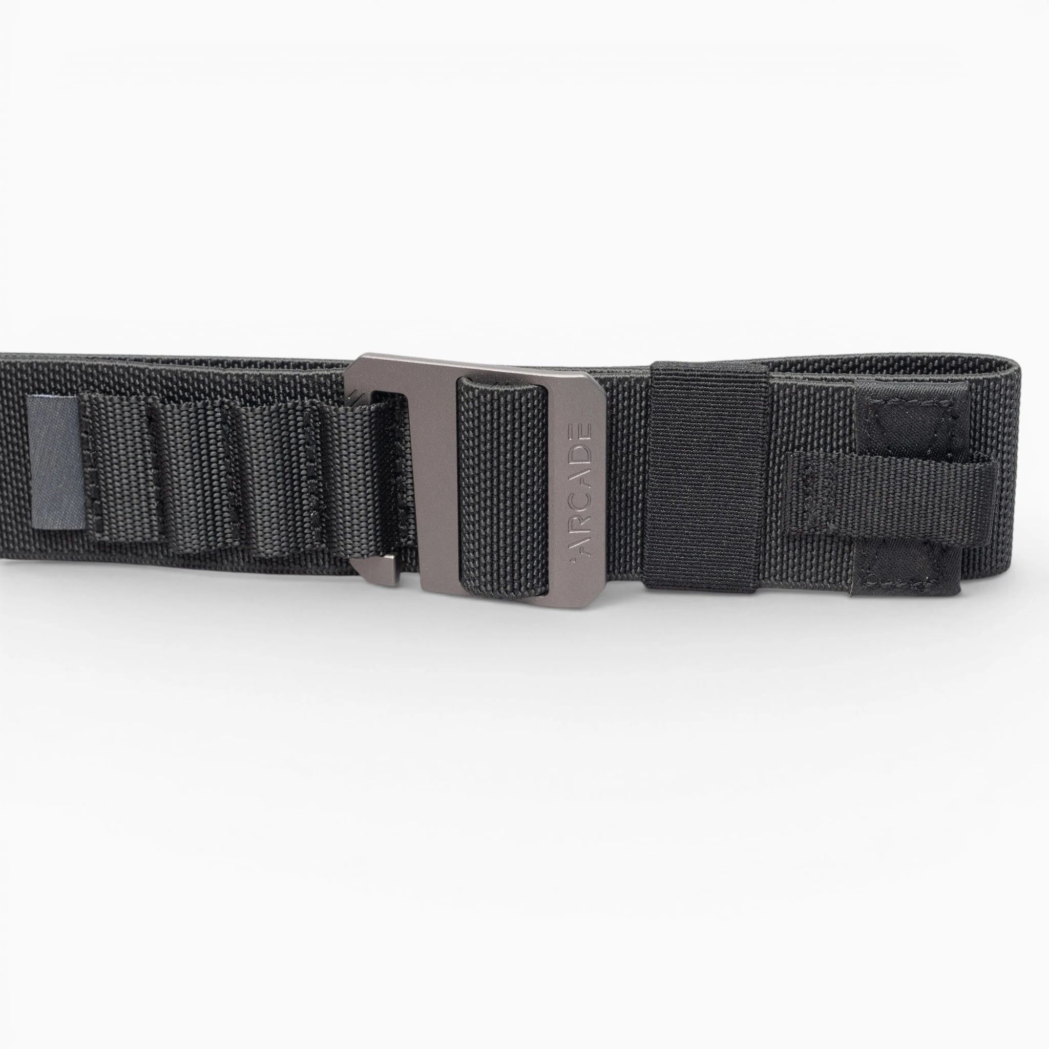 The Arcade Belts Hardware Alu is a black nylon low-profile belt with a metal buckle, shown on a white background. It features reinforced stitching and looped sections for extra durability, making it ideal for travel enthusiasts.