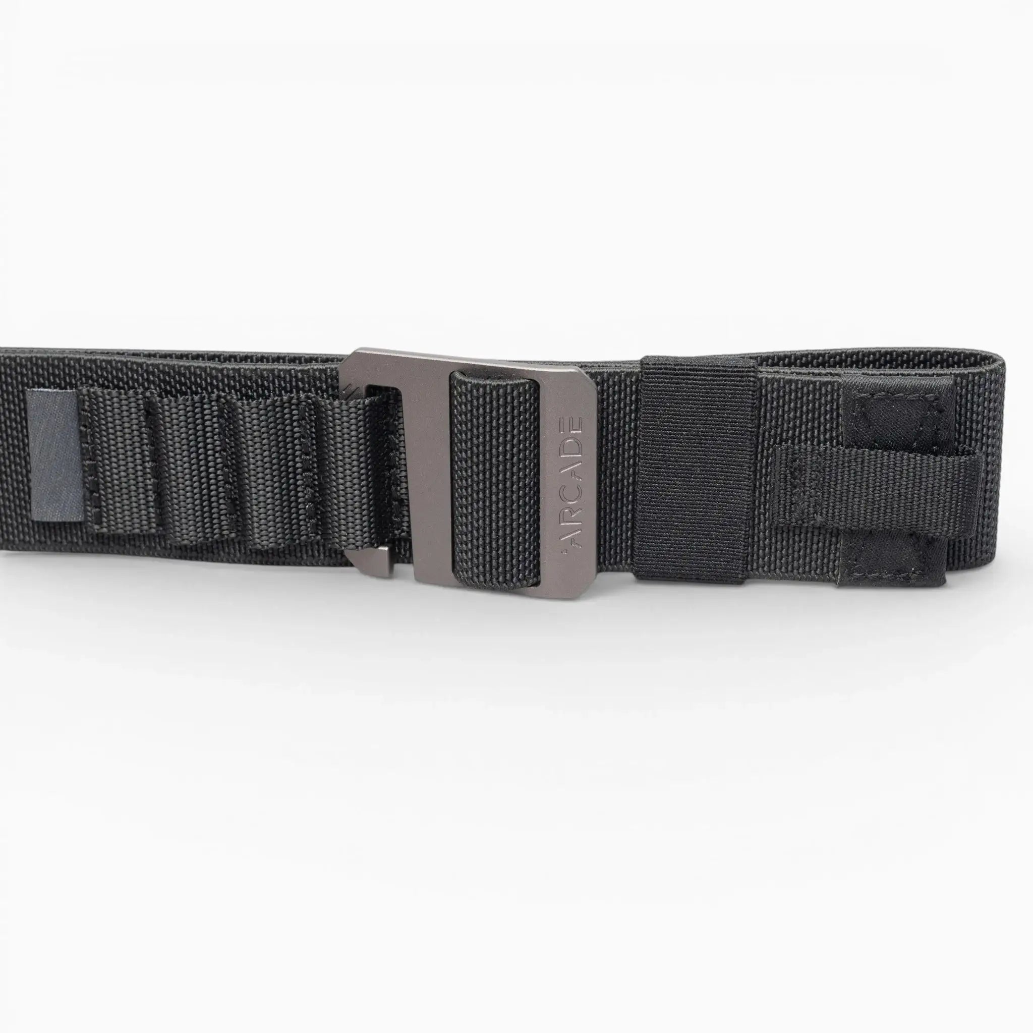 The Arcade Belts Hardware Alu is a black nylon low-profile belt with a metal buckle, shown on a white background. It features reinforced stitching and looped sections for extra durability, making it ideal for travel enthusiasts.