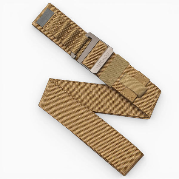 The Arcade Belts Hardware Alu is a tan nylon tactical travel belt featuring a plastic buckle and Velcro closure, shown partially folded on a white background.