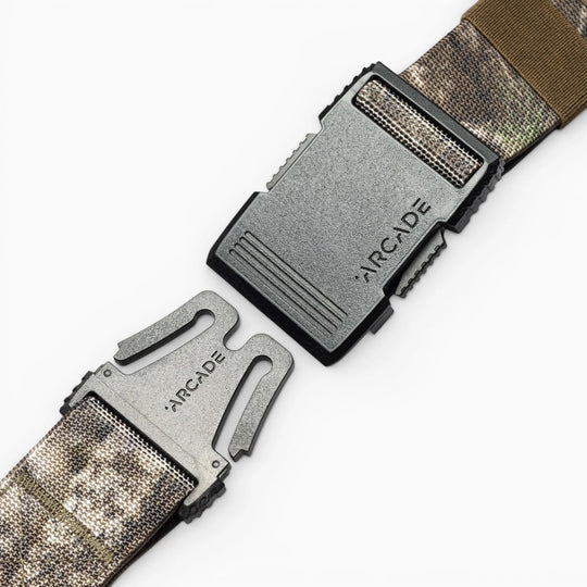 Two segments of the Arcade Belts Hardware low profile belt with a black plastic buckle, both engraved with the Arcade Belts name, are shown against a white background.