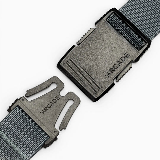 Close-up of a grey fabric Arcade Belts Hardware belt with a black plastic buckle, both parts separated and facing each other, showcasing the product’s superior strength and modern style.