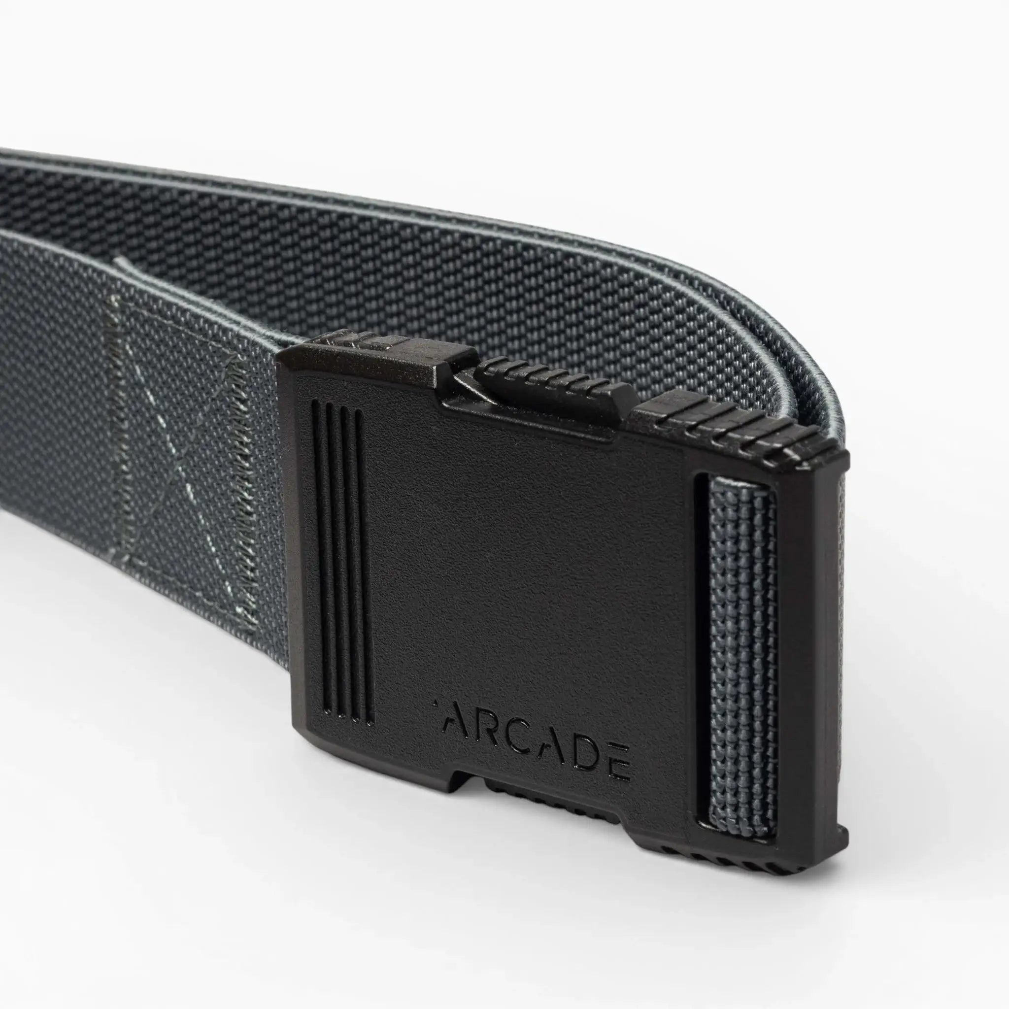 A close-up of the gray Arcade Belts Hardware belt highlights its superior strength and a rectangular black plastic buckle engraved with "ARCADE," set against a plain light-colored background.