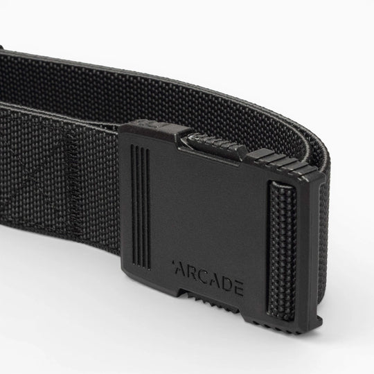 Close-up of the Arcade Belts Hardware belt with a rectangular plastic buckle and ARCADE embossed on it, highlighting its superior strength against a plain light background.
