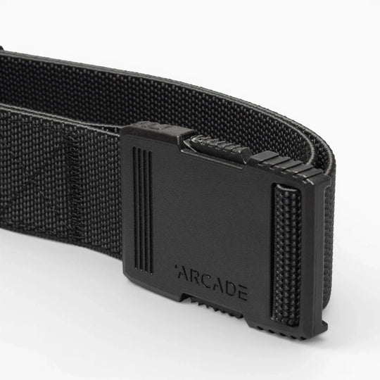 Close-up of the Arcade Belts Hardware belt with a rectangular plastic buckle and ARCADE embossed on it, highlighting its superior strength against a plain light background.
