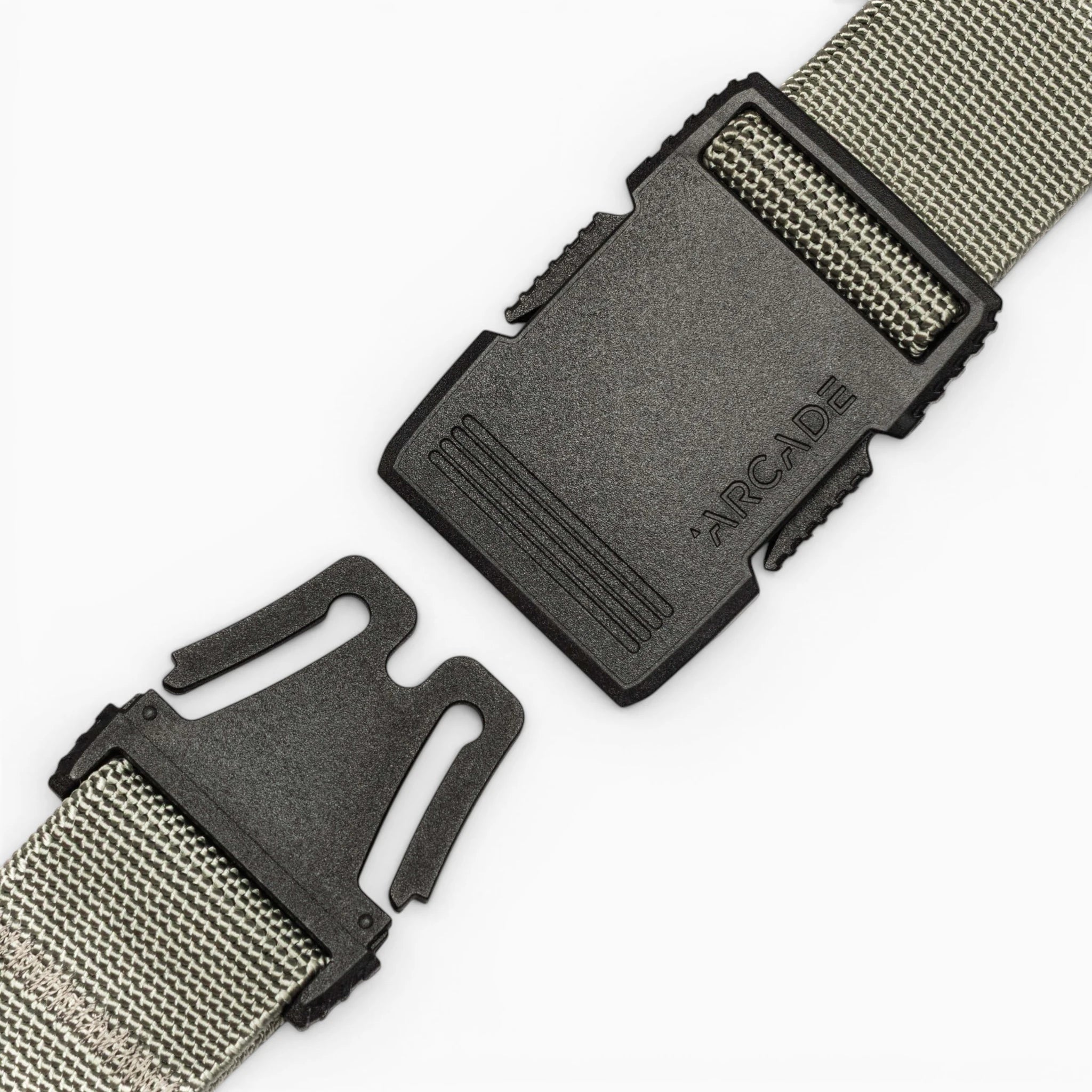 A close-up of the gray Arcade Belts Hardware belt features a black plastic buckle with "ARCADE" embossed, shown partially unclasped against a plain white background.