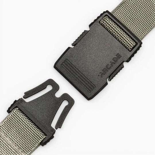 A close-up of the gray Arcade Belts Hardware belt features a black plastic buckle with "ARCADE" embossed, shown partially unclasped against a plain white background.
