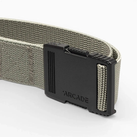 A close-up of the gray Hardware belt by Arcade Belts, featuring superior strength and a black plastic buckle engraved with ARCADE, shown against a light background.
