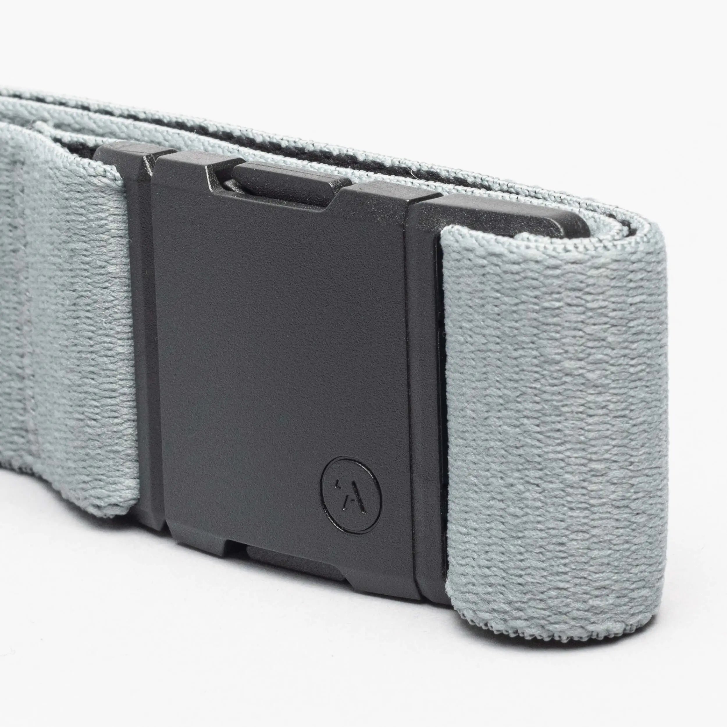 A close-up of an Arcade Belts Island Collection belt in light gray, featuring a low-profile matte black rectangular buckle with a small circular logo and textured stretch webbing fabric.