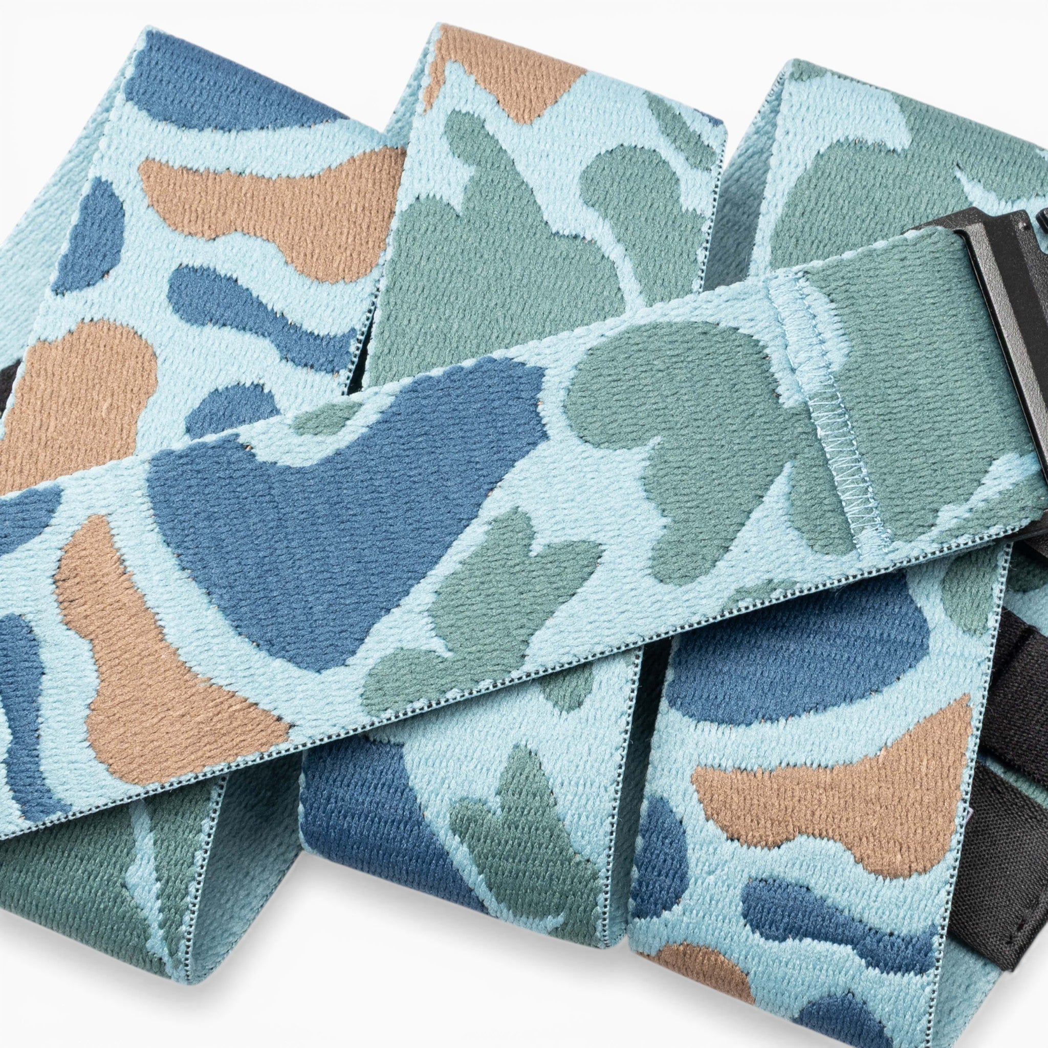 A close-up of the Arcade Belts High Fives Duck Camo fabric belt, featuring a blue, green, and tan camouflage pattern with a black rectangular buckle—perfect for veterans or anyone looking to support athletes through organizations like the High Fives Foundation.