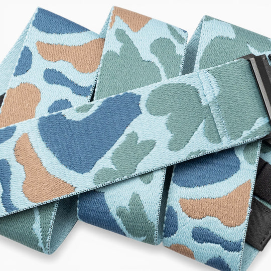 A close-up of the Arcade Belts High Fives Duck Camo fabric belt, featuring a blue, green, and tan camouflage pattern with a black rectangular buckle—perfect for veterans or anyone looking to support athletes through organizations like the High Fives Foundation.