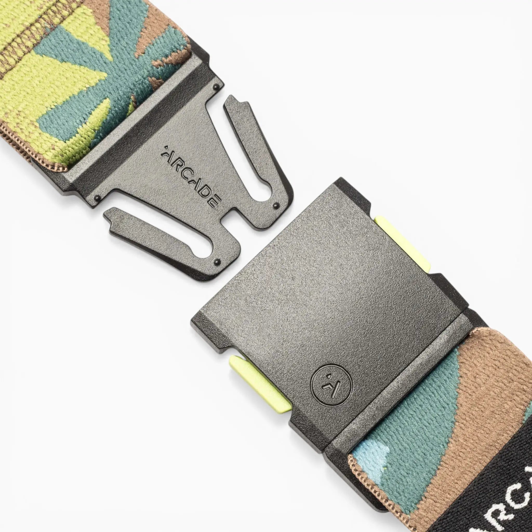 Close-up of the Arcade Belts Inkstorm, a patterned performance stretch webbing belt in green, brown, and tan hues. Partially unclasped, its black plastic A2 buckle displays the ARCADE branding. Designed for flexibility and comfort, this movement-ready belt ensures a perfect fit for any adventure.