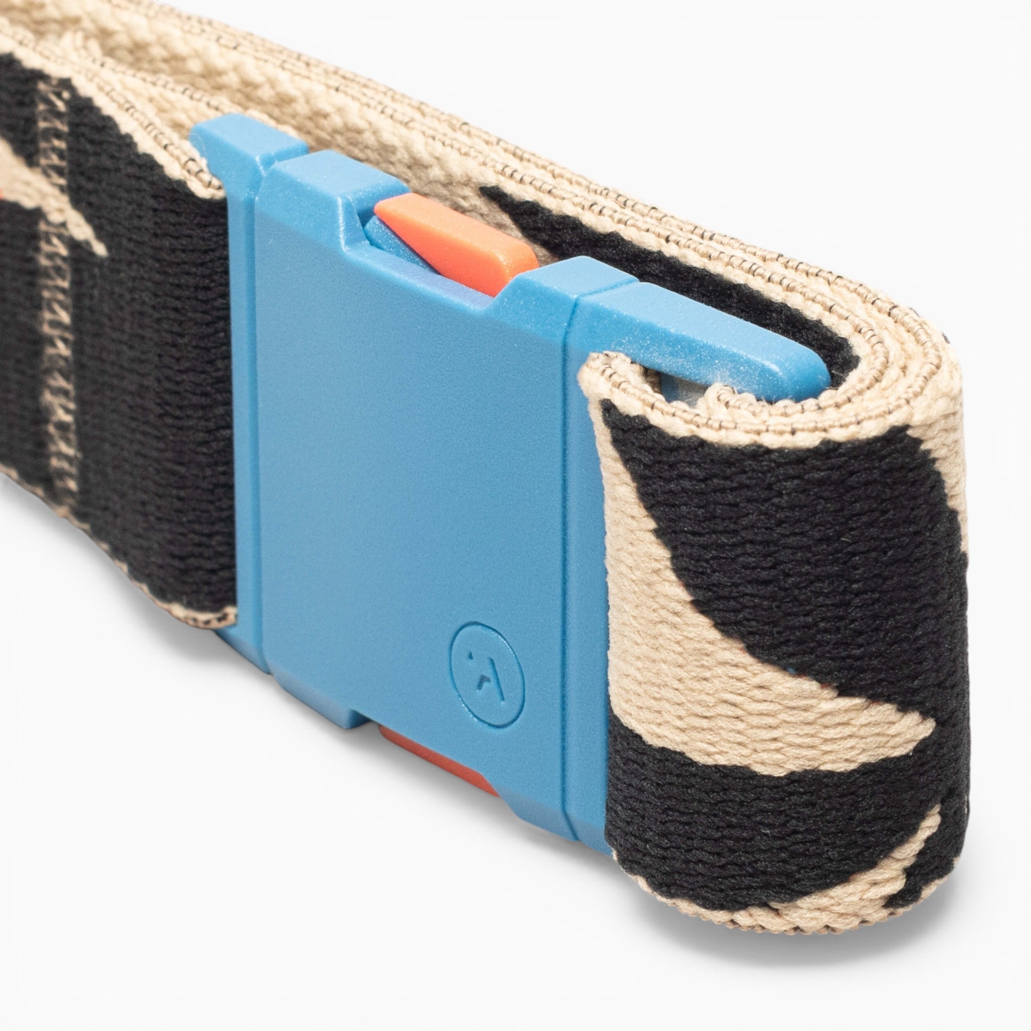 A close-up of the Arcade Belts Inkstorm strap highlights its beige and black patterned performance stretch webbing, neatly coiled and set against a plain white background. The strap features a blue plastic A2 buckle with a small orange slider.