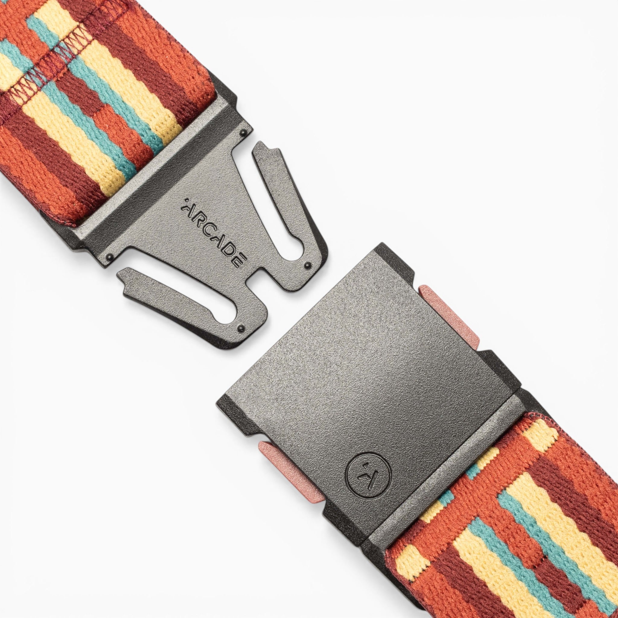 A close-up of the Vernan Kee belt from Arcade Belts, featuring a colorful, striped fabric with a design inspired by traditional rug patterns. The black metal clasp is partially open, revealing the Arcade Belts branding on one side.