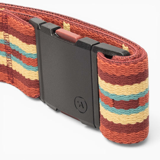 A close-up of the Arcade Belts Vernan Kee belt, featuring a black rectangular buckle and a woven strap with red, yellow, brown, and teal horizontal stripes inspired by traditional rug patterns.