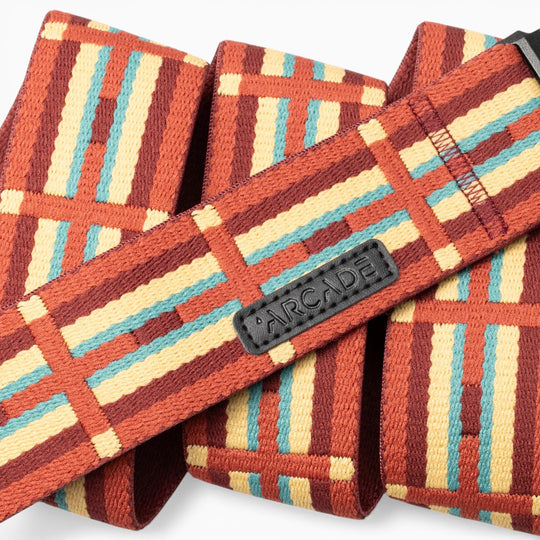 A close-up of the Vernan Kee belt by Arcade Belts showcases geometric shapes inspired by Navajo rug patterns in red, yellow, turquoise, and brown. The black Arcade label is stitched onto the belt, highlighting Vernan Kee’s artistic influence.