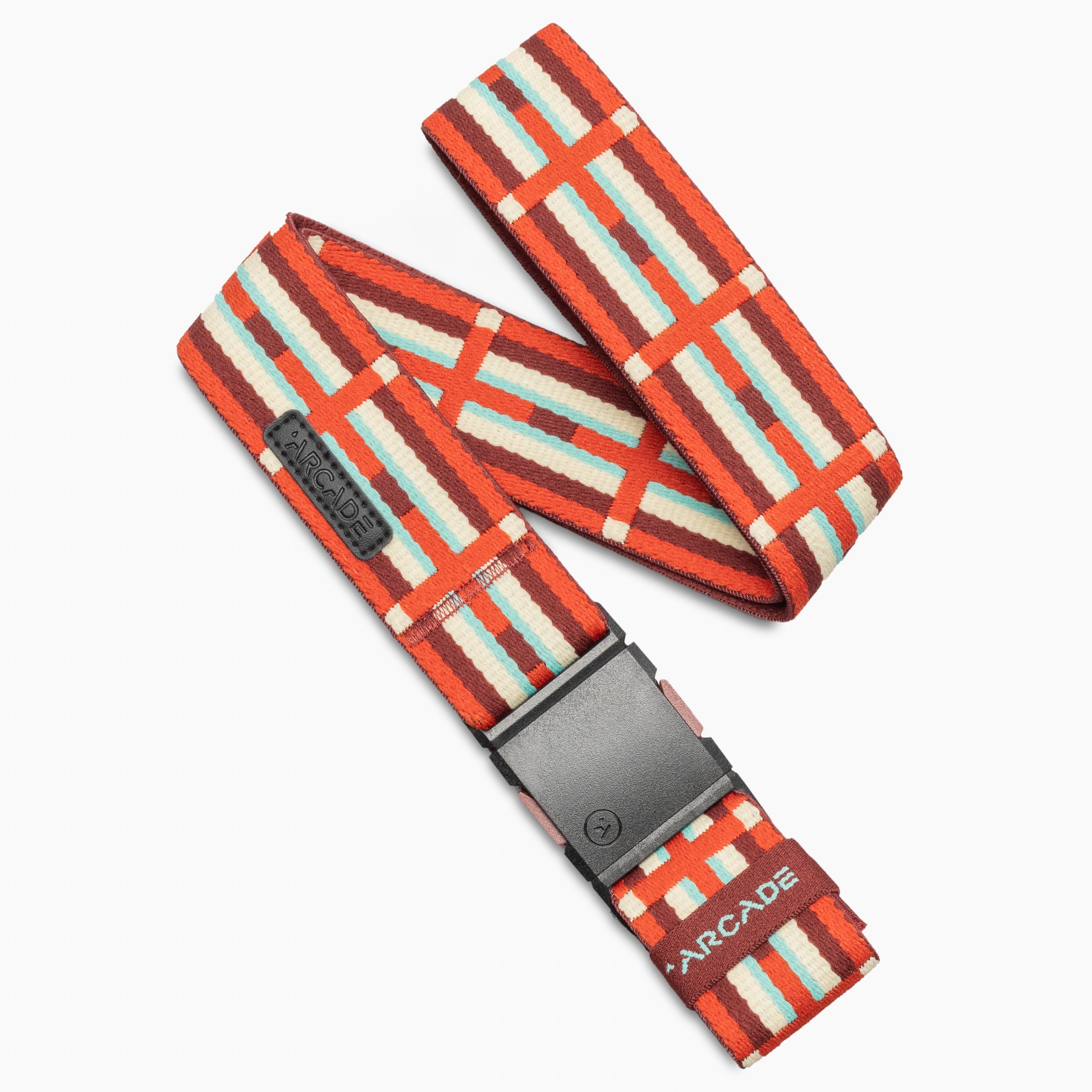 A striped fabric belt in Mesa Amber with red, white, orange, and teal accents, featuring a black buckle. Inspired by traditional rug patterns and Navajo heritage, the Vernan Kee design from Arcade Belts showcases bold geometric lines. The word “ARCADE” appears on a label near the buckle.
