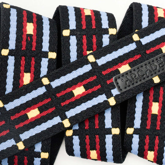 A close-up of the Arcade Belts Vernan Kee woven strap showcases a geometric pattern in black, blue, red, and yellow with a small ARCADE tag—an ideal elastic stretch belt for travel or daily use.